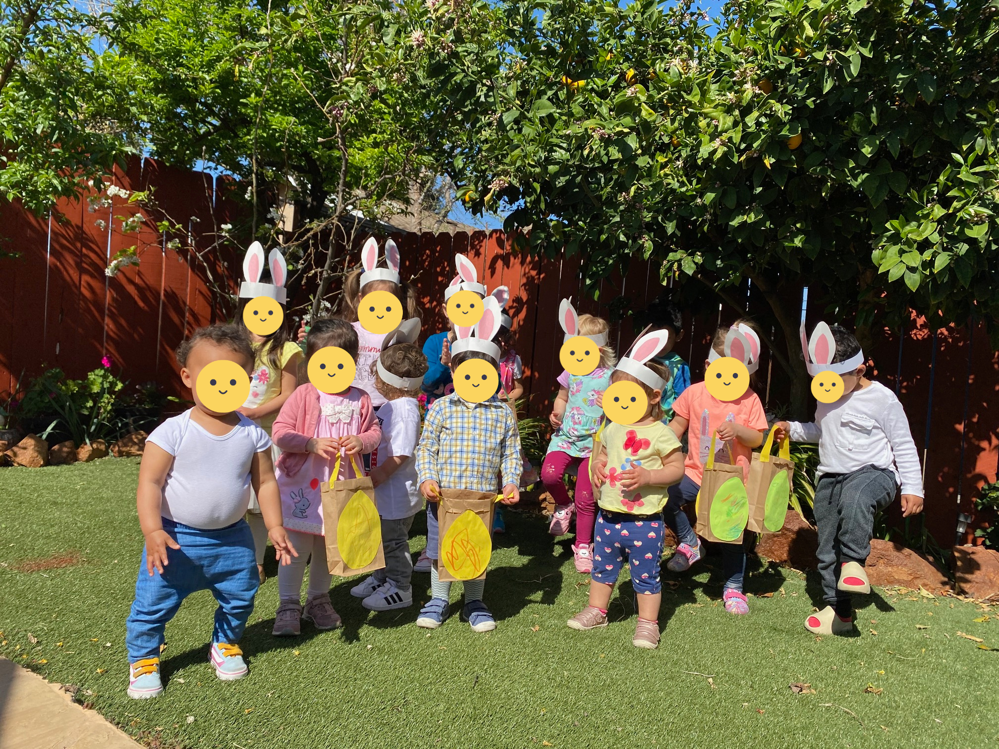 Children smiling at the camera with constructed bunny ear headbands.